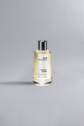 Elegant glass bottle of Cedrat Boise Yellow Dessin perfume with pale yellow liquid and black cap displayed against a soft gray background.