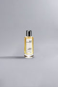 Minimalist image of a luxury perfume bottle filled with golden liquid on a gray background, showcasing Coco Vanille Yellow Dessin in an elegant, high fashion style.