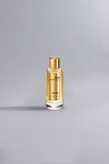 Holidays Gold luxury perfume bottle with golden liquid and cap displayed on a minimalist light gray background, representing high fashion elegance.