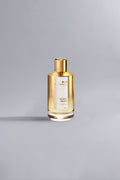 Instant Crush Gold perfume bottle with a sleek gold cap and liquid inside, showcased against a minimalist gray background highlighting its luxury and high fashion appeal.