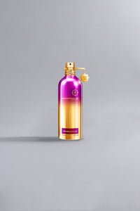 A luxury perfume bottle with a metallic gradient finish transitioning from dark purple at the top to gold at the bottom, labeled Orchid Powder Dark Purple.