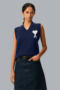 Woman wearing a navy sleeveless top with a logo on a gray background