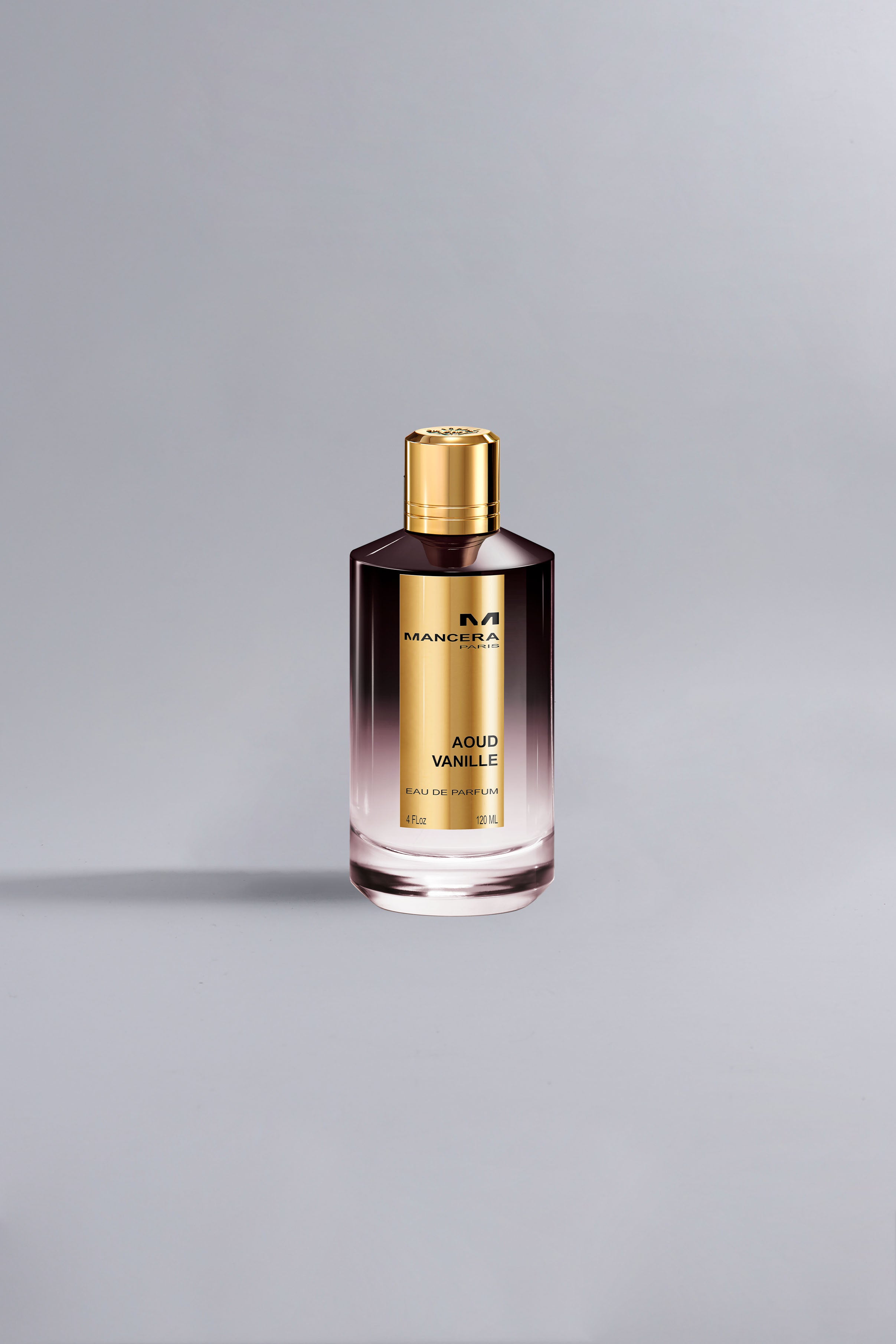 A sleek bottle of Aoud Vanille Dark Purple fragrance with a gradient dark purple to clear glass design and a shiny gold cap against a light gray background.