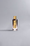 A sleek perfume bottle with a gold cap and label, featuring the fragrance name Aoud Vanille Dark Purple, set against a minimalistic grey background.