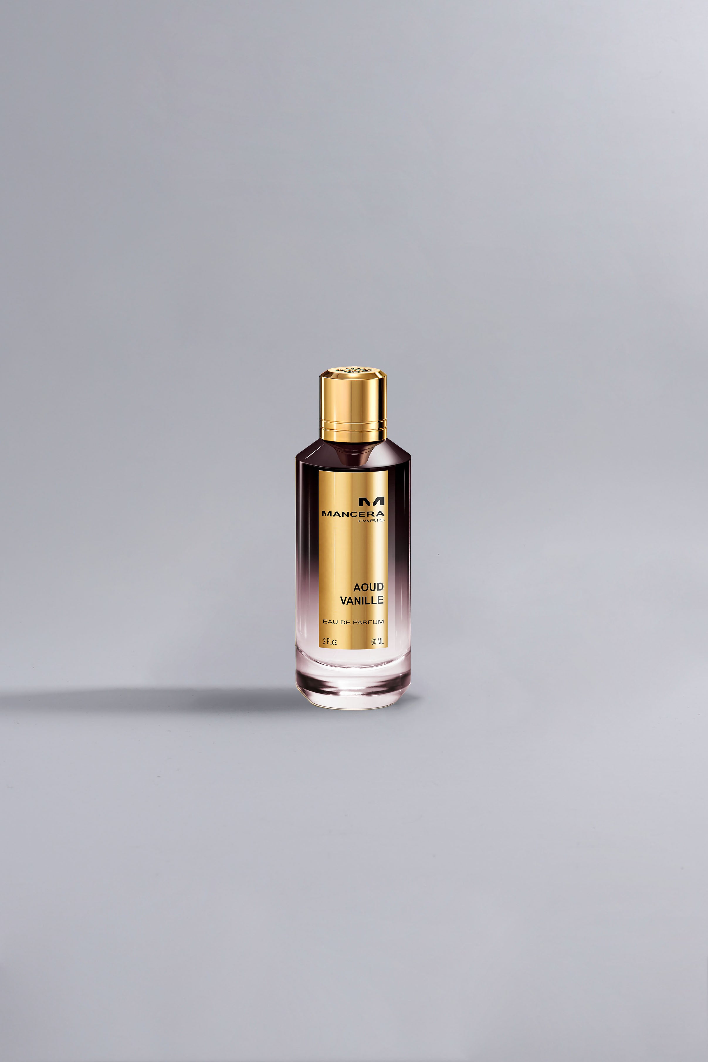 A sleek perfume bottle with a gold cap and label, featuring the fragrance name Aoud Vanille Dark Purple, set against a minimalistic grey background.