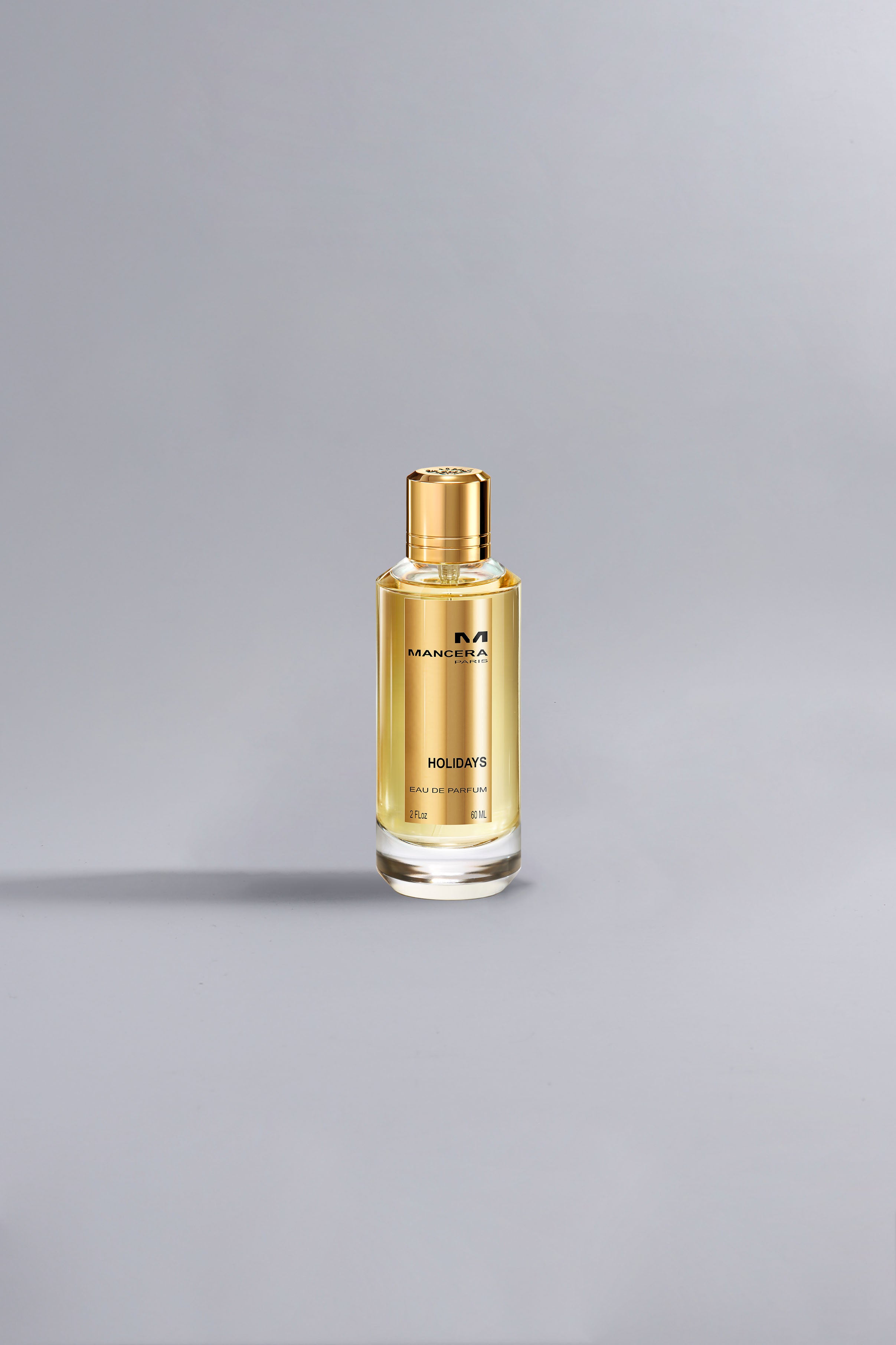 Holidays Gold luxury perfume bottle with golden liquid and cap displayed on a minimalist light gray background, representing high fashion elegance.