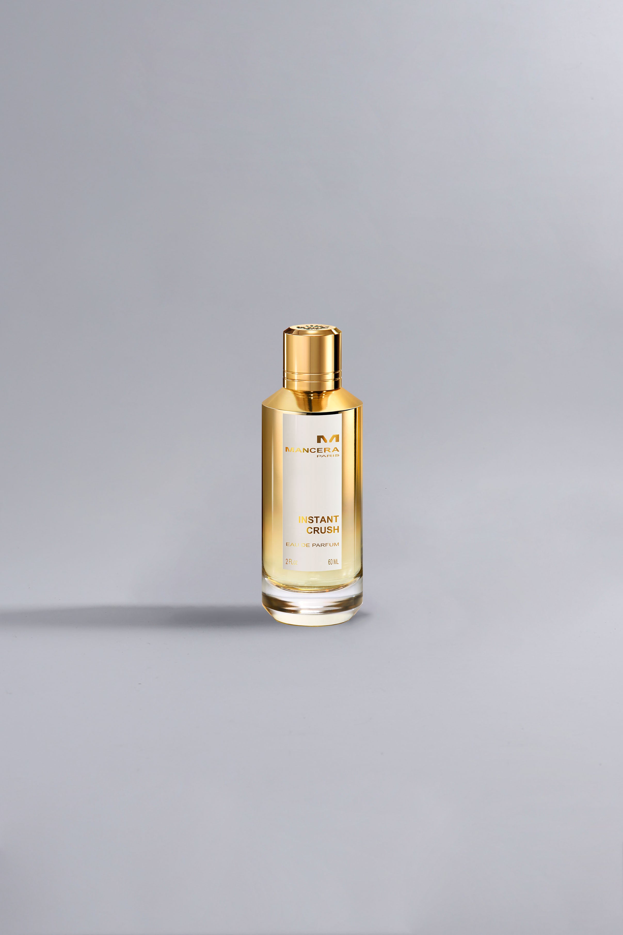 Luxurious gold-accented perfume bottle labeled Instant Crush Gold standing on a smooth gray surface, showcasing elegant high fashion design.