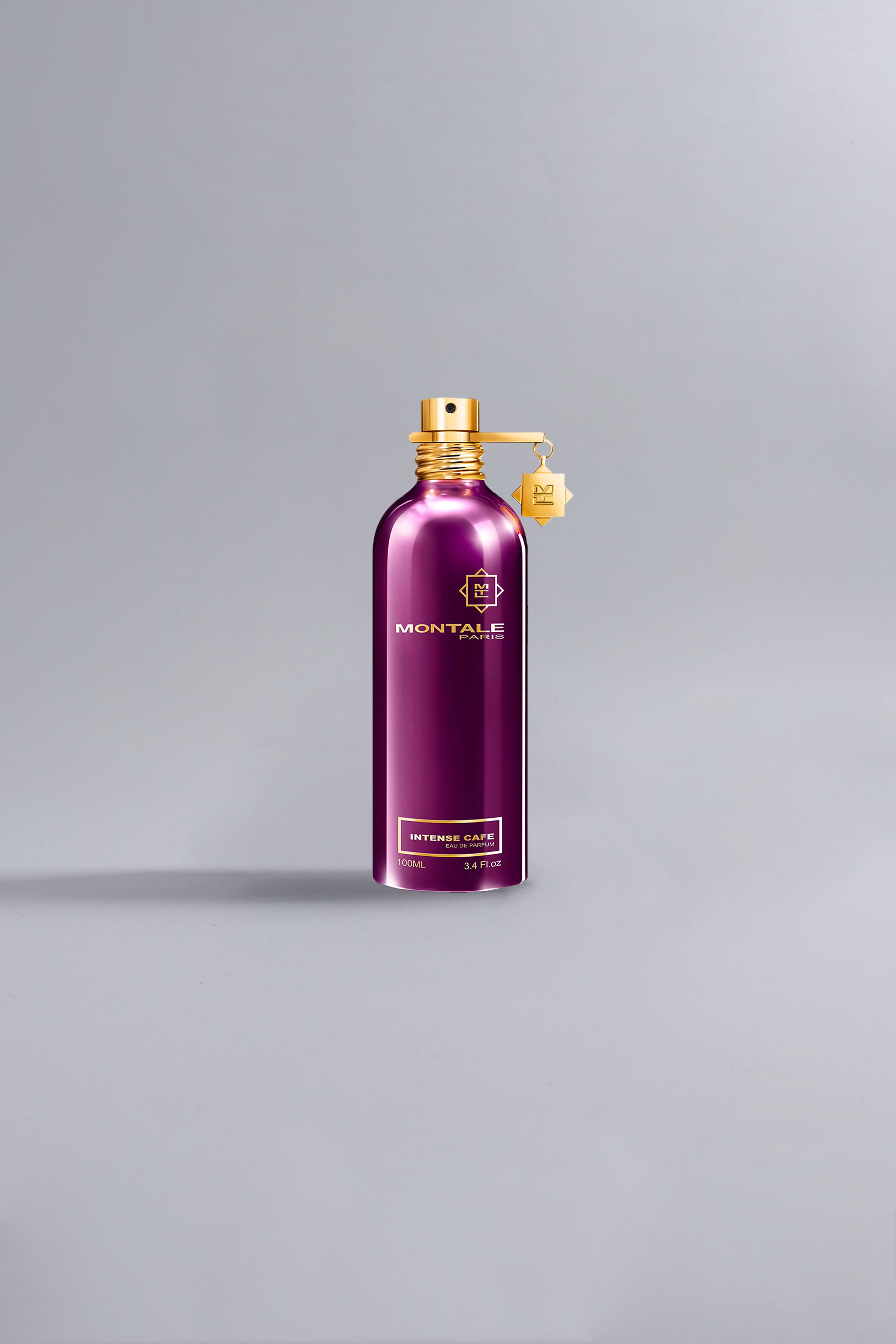 Elegant metallic spray bottle in rich dark purple with gold accents, showcasing the Intense Café Dark Purple fragrance from Montale, embodying luxury and high fashion.
