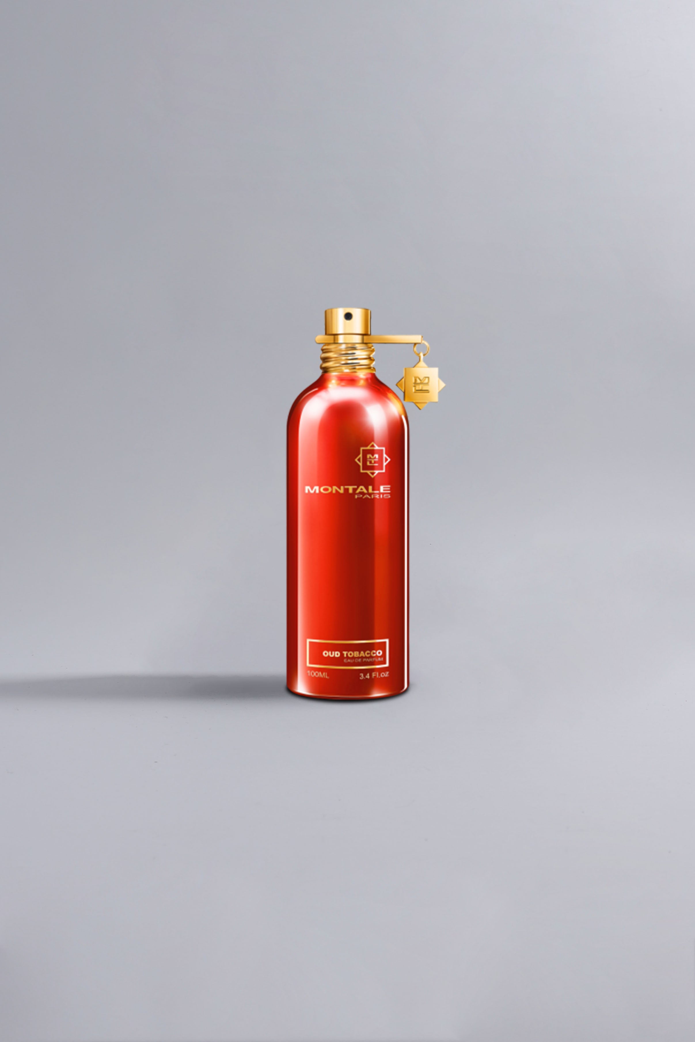 Sleek and elegant red bottle of Oud Tobacco Red perfume with gold spray top and charm, presented against a minimalist gray background.