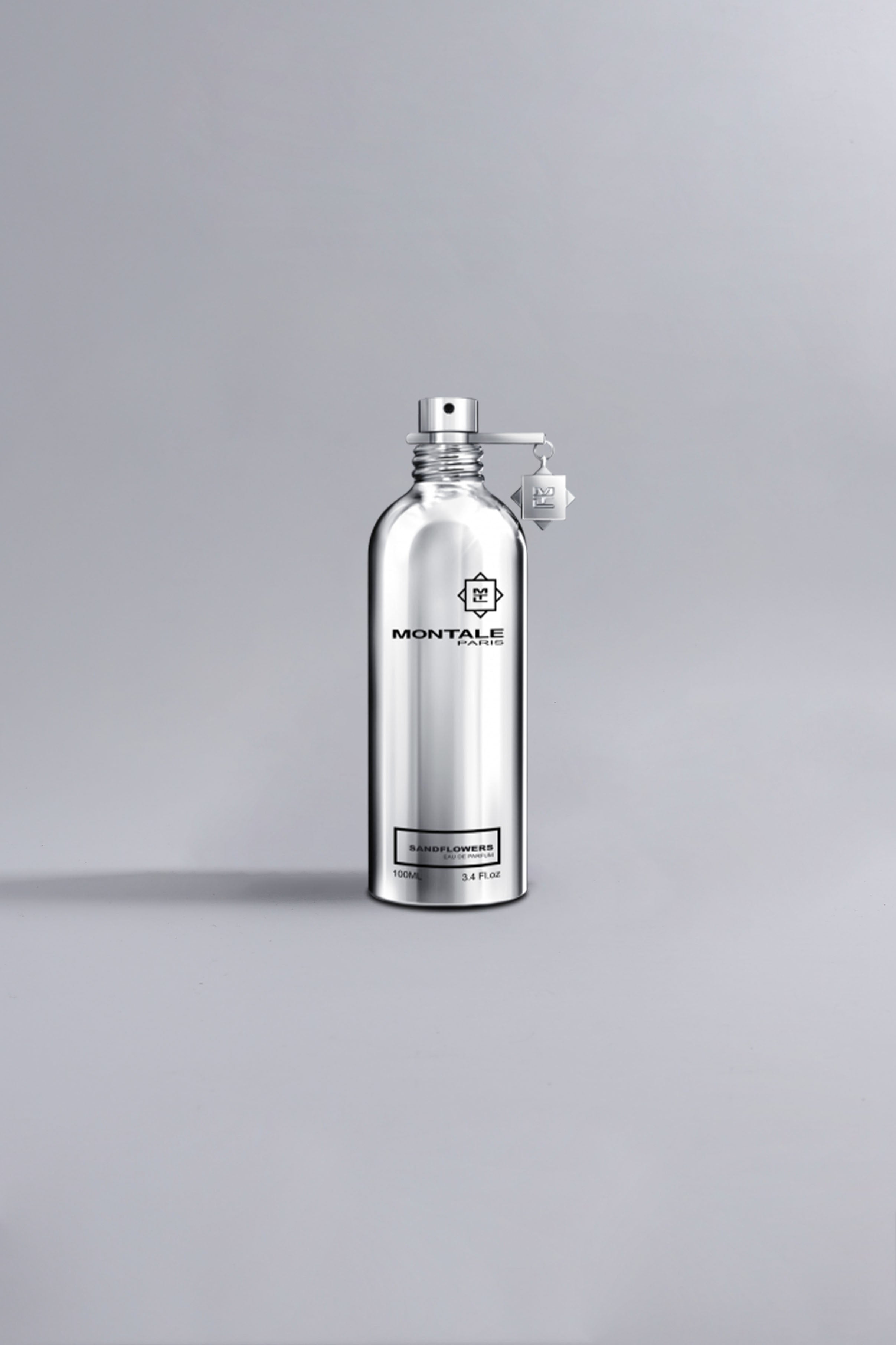 Silver metallic spray bottle of luxury fragrance Sandflowers Silver displayed on a minimalist gray background, highlighting sleek and modern design.