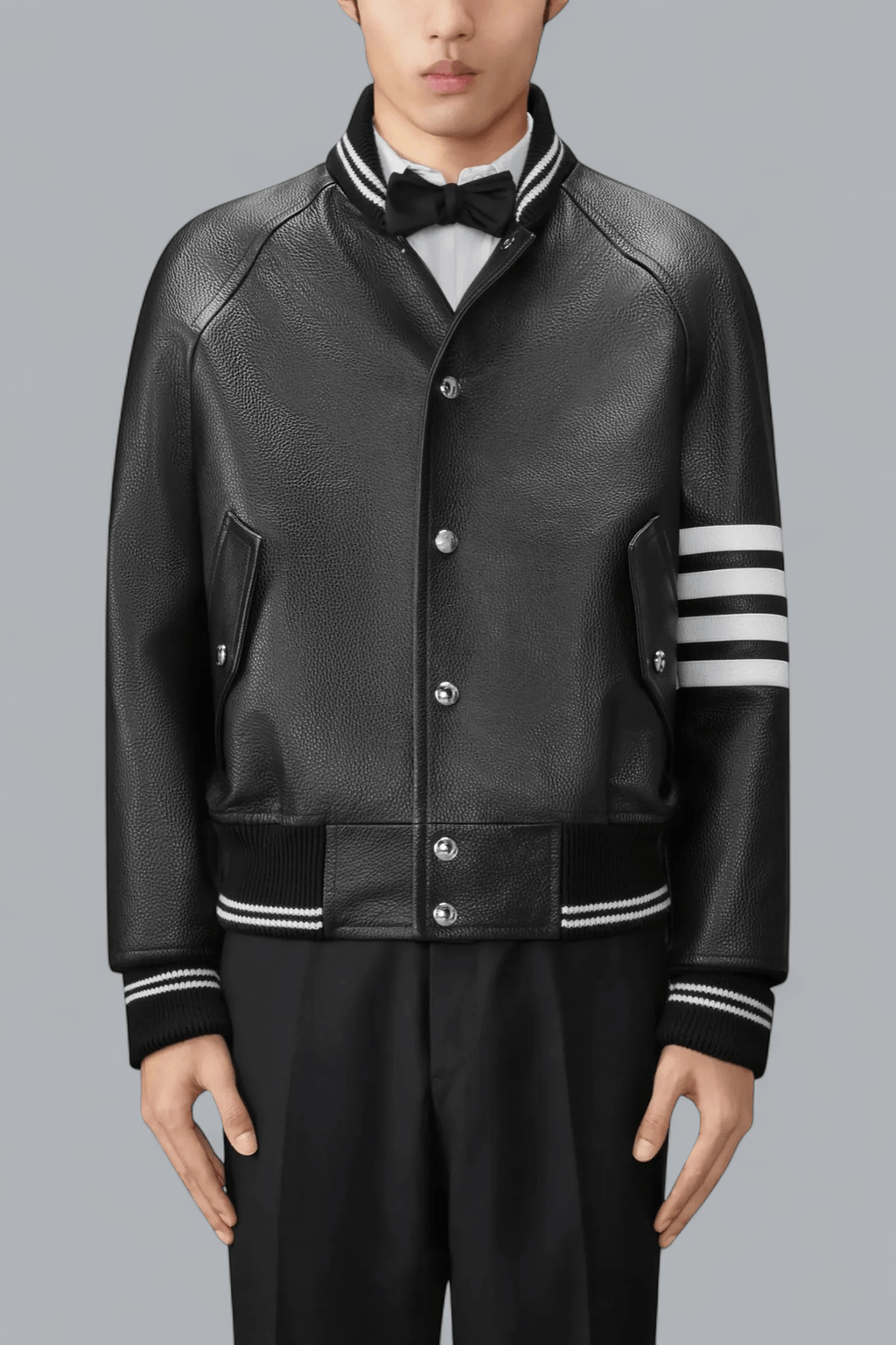 Black leather varsity jacket with white stripes on sleeves against a gray background