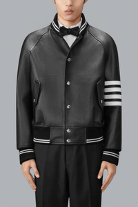Black leather varsity jacket with white stripes on sleeves against a gray background