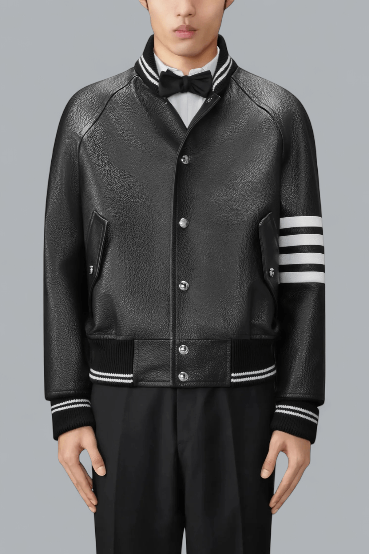 Black leather varsity jacket with white stripes on sleeves against a gray background