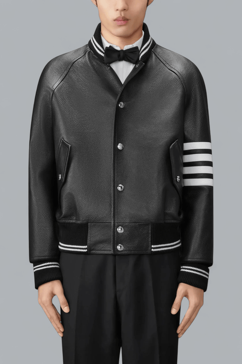 Black leather varsity jacket with white stripes on sleeves against a gray background